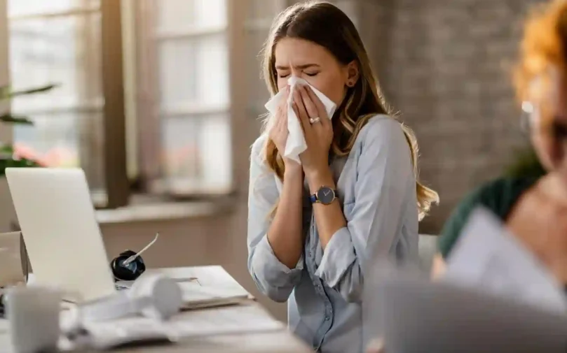 young-sick-businesswoman-sneezing-tissue-while-working-office